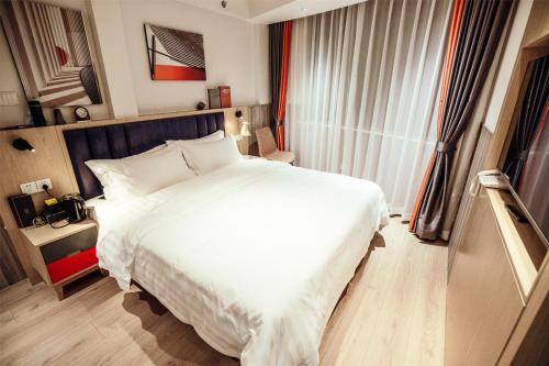 a bedroom with a large white bed and a window at Shanghai Fish Inn People Square in Shanghai