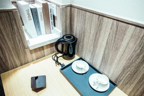 a table with a phone and two cups and plates on it at Shanghai Fish Inn People Square in Shanghai