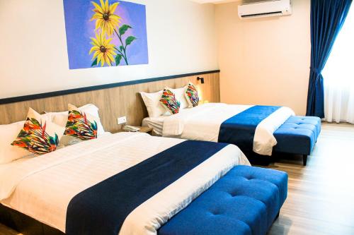 a hotel room with two beds and a blue ottoman at Savana Hotel & Serviced Apartments in Kuala Perlis
