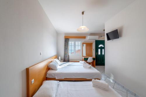 a hotel room with two beds and a tv at Naftilos Studios in Lourdata