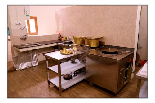 a kitchen with a stove and some pots and pans at The Ranikhet Continental in Rānīkhet