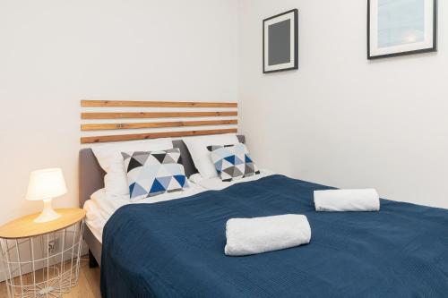 1 dormitorio con 1 cama grande con sábanas y almohadas azules en Apartments Gdynia Władysława IV by Renters, en Gdynia