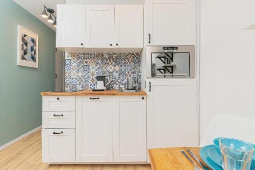 a kitchen with white cabinets and a table at Apartments Gdynia Władysława IV by Renters in Gdynia