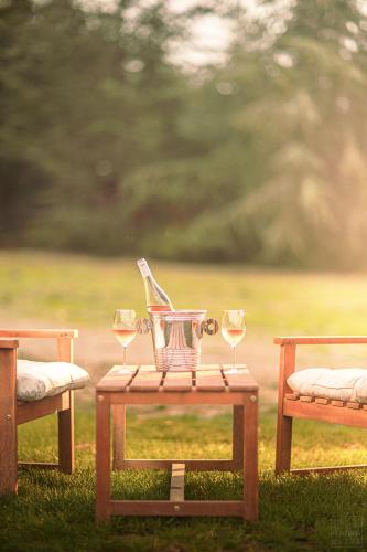 a picnic table with wine glasses and a basket on it at Domaine de la Vitarelle Glamping in Villanière