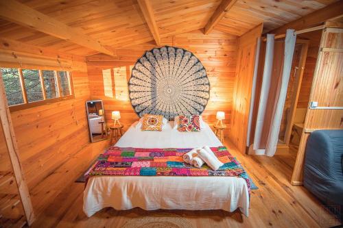 a bedroom with a large bed in a wooden cabin at Domaine de la Vitarelle Glamping in Villanière