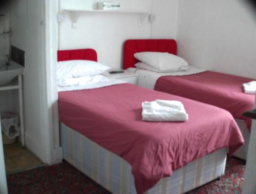 two beds in a room with pink sheets and white towels at Jollies Hotel in Blackpool