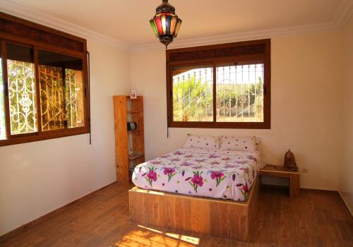 1 dormitorio con 1 cama y 2 ventanas en Maison d hôtes Bungalow Villa Hammam Bien-être et Piscine, en Agadir