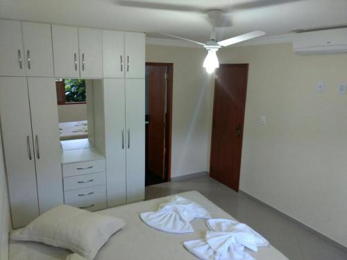 a bedroom with white cabinets and towels on a bed at Pousada Casa do Jova em Raposo RJ 