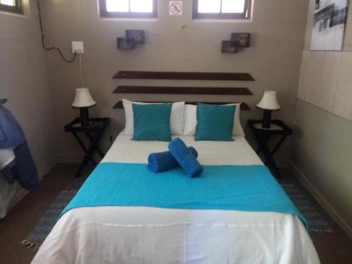 a bedroom with a large bed with blue pillows at Oasis Country Lodge in Klawer