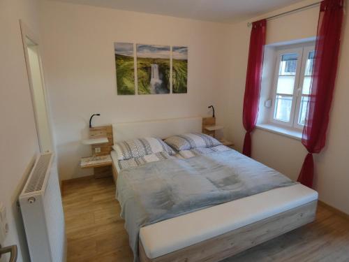 a bedroom with a large bed with red curtains at Gästezimmer Gombotz in Etmissl