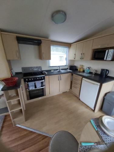 
a kitchen with a stove a sink and a refrigerator at Caravan on the Devon\Cornwall border in Stratton
