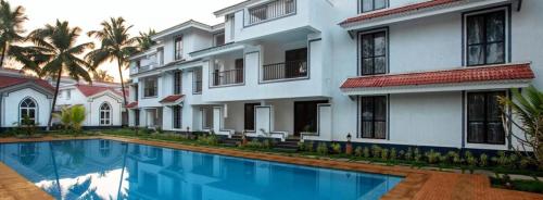 a building with a swimming pool in front of a building at Riviera Sublime Holiday Homes in Siolim