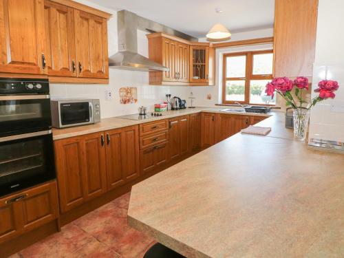 a kitchen with wooden cabinets and a counter with roses at Dooneen in Skibbereen