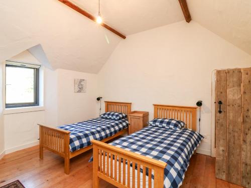 two beds in a room with wooden floors and a window at Dairy Lane Cottage in Bunclody