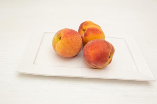 three peaches and two pears on a white plate at Hotel Ramos Mejía in Mar del Plata