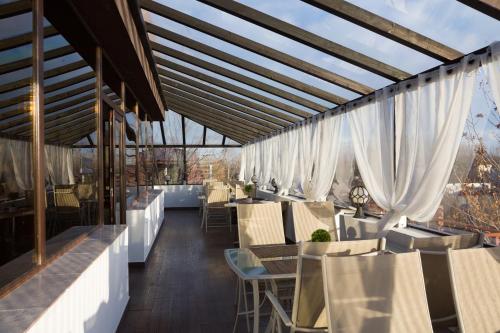 a restaurant with white curtains and tables and chairs at Hotel Charter Otopeni in Otopeni