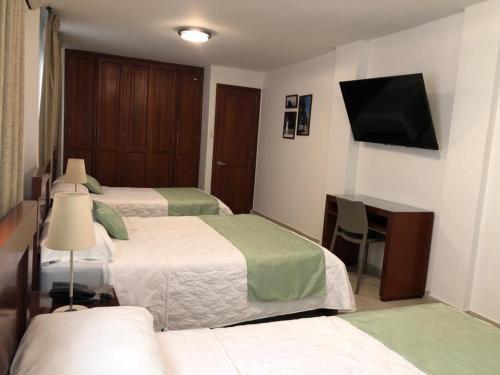 a hotel room with two beds and a desk and a television at Colon Plaza Hotel in Tumaco