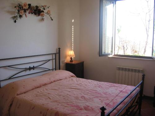 ein Schlafzimmer mit einem Bett mit einer rosa Decke und einem Fenster in der Unterkunft Villa Righino in Murlo