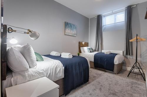 a bedroom with two beds and a couch and a window at Murray Nest #2 - TV in Every Bedroom! in Llanelli