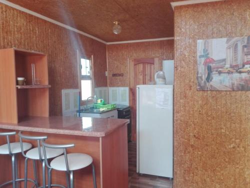 a kitchen with a white refrigerator and some bar stools at Estancia Pacífico in Punta de Choros