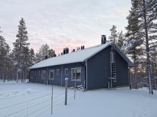 una casa azul en la nieve con una valla en Gold Legend Paukkula #3 - Saariselkä Apartments, en Saariselkä