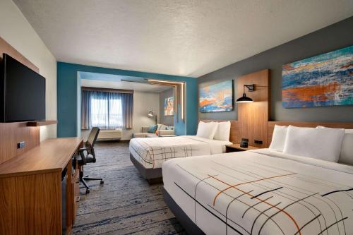 a hotel room with two beds and a flat screen tv at La Quinta Inn & Suites by Wyndham Springfield in Springfield