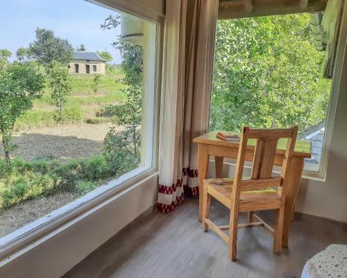 a wooden chair sitting at a desk in front of a window at Seclude Palampur in Pālampur
