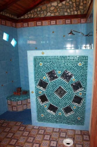 a blue tiled bathroom with a mosaic tile wall at Cascata Del Bosco Cabinas in San Vito