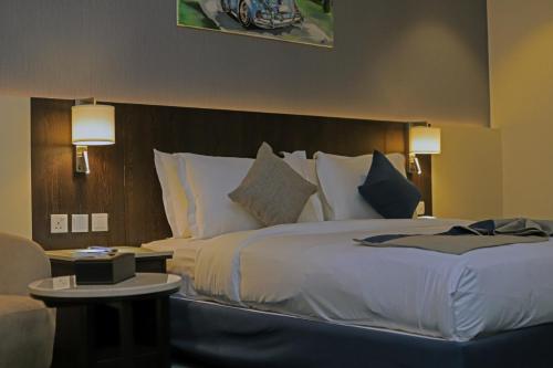 um quarto de hotel com uma cama grande e uma cadeira em Coupard Hotel em Riade