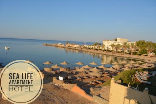 ein Strand mit Sonnenschirmen und ein Apartmenthotel am Meer in der Unterkunft Boulevard Apartment Hotel in Hurghada