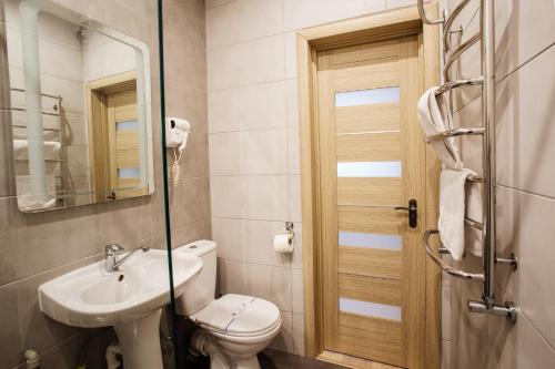 a bathroom with a sink and a toilet and a mirror at Discovery Hotel in Lviv