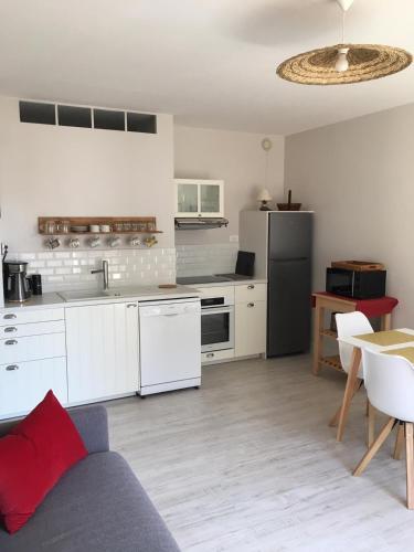 une cuisine avec des armoires blanches et un réfrigérateur noir dans l'établissement Nausicaa, à Trouville-sur-Mer