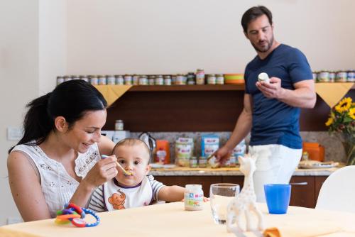 a woman and a baby sitting at a table eating food at Aparthotel Imperial in Bibione