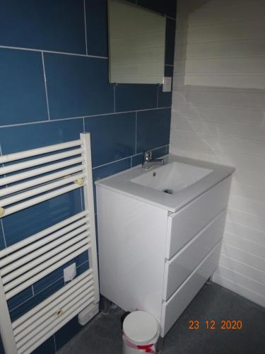 La salle de bains est pourvue d'un lavabo blanc et d'un mur carrelé bleu. dans l'établissement La Bresse Hautes Vosges Chalet Le Podent, à La Bresse