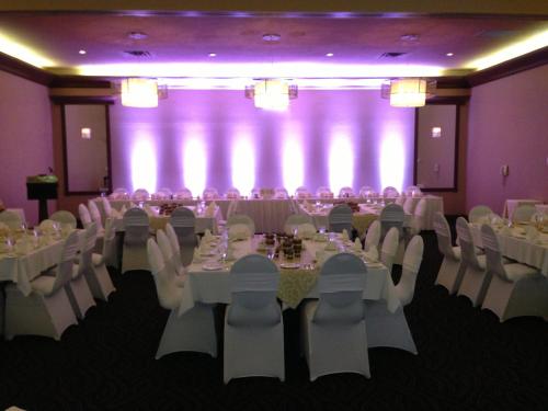 a banquet hall with white tables and chairs and purple walls at Atlantic Host Hotel, Trademark Collection by Wyndham in Bathurst