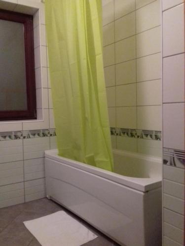 City View Apartment في فوينيتسا: حمام مع حوض استحمام مع ستارة دش خضراء