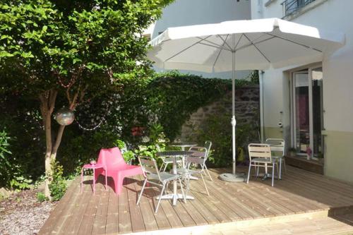 a patio with tables and chairs and an umbrella at Little Lodge Hôtel in Brest