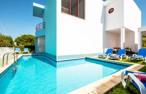 einen Pool mit blauen Stühlen und ein Haus in der Unterkunft Villa Marina in Albufeira