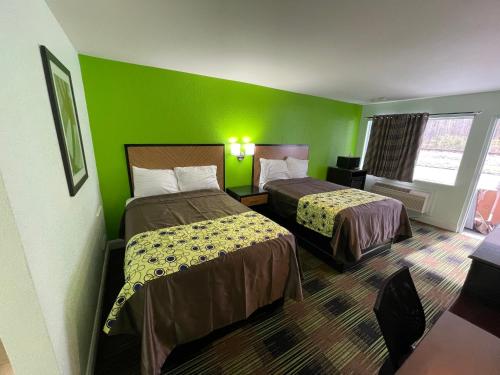 Bowers Hill Inn Chesapeake في تشيسابيك: غرفة فندقية بسريرين وجدار أخضر