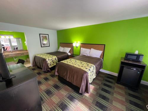 Bowers Hill Inn Chesapeake في تشيسابيك: غرفة فندقية بسريرين وجدران خضراء