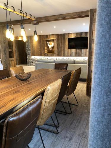a dining room with a wooden table and leather chairs at Résidence Julianna , trajets remontées mécaniques , livraison viennoiseries, piscine couverte in Morzine