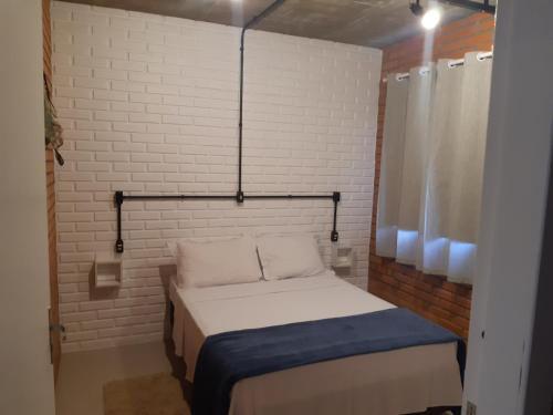 a small bedroom with a bed and a brick wall at Casa Esquina do Mar in São Francisco do Sul