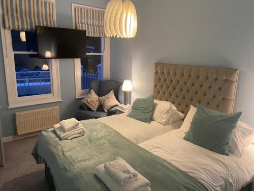 a bedroom with two beds and a couch and a tv at 3, Glenthorne House, Salcombe in Salcombe