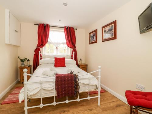 a bedroom with a white bed with red pillows at Wee Woody in Bentley