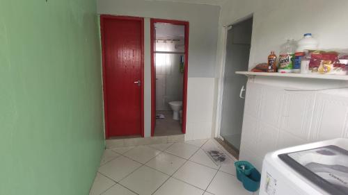 a bathroom with a red door and a toilet at Space Hostel , quartos privativos in Arraial do Cabo