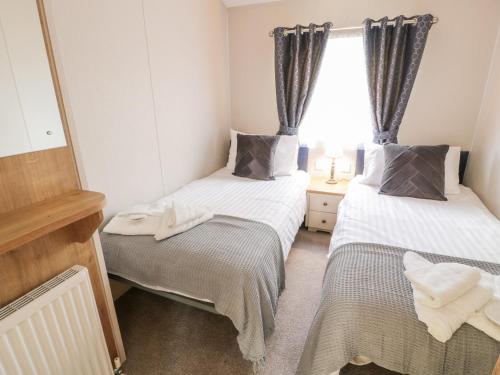 two beds in a small room with a window at Serenity Lodge in Wemyss Bay