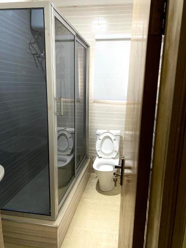 a bathroom with a toilet and a walk in shower at Nue-Crest Hotels & Suites in Enugu