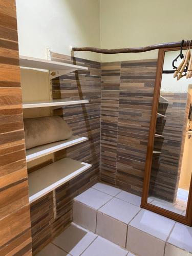 a walk in shower with wooden walls and shelves at Casa do Ney in Fernando de Noronha