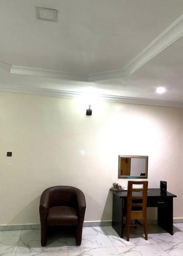 a living room with a chair and a desk at Nue-Crest Hotels & Suites in Enugu