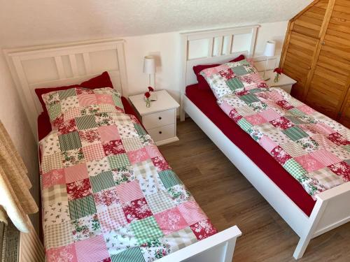 um quarto com 2 camas com colchas vermelhas e verdes em Ferienwohnung-bei-Familie-Kuehl em Fehmarn